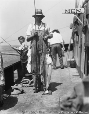 Man posing with fishing rod and fish caught from Point Loma fishing barge