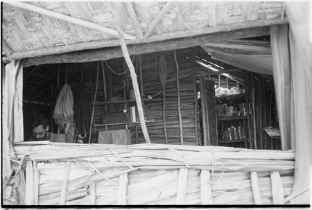 Roy Rappaport at work in his Tsembaga house, cans of food and other supplies at right