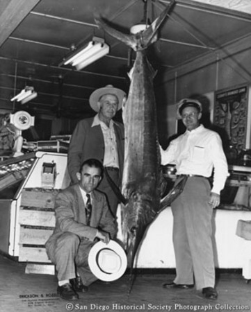 Three men posing with [swordfish?] catch