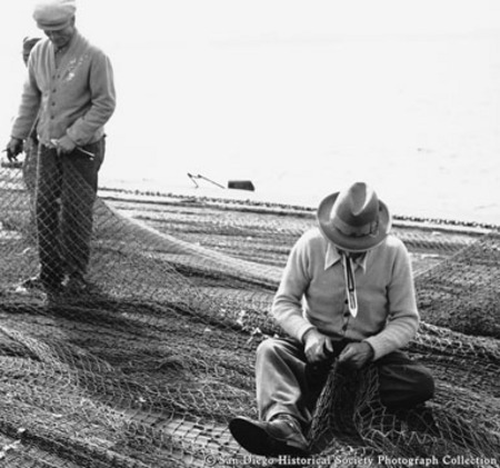 Two men mending fishing nets on Embarcadero at foot of Grape Street