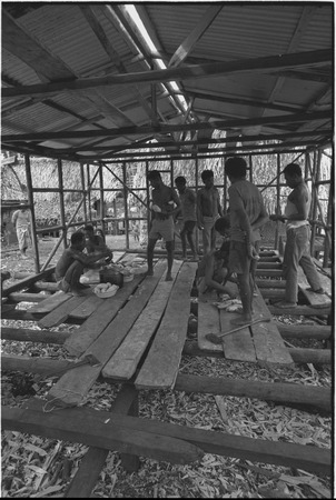 Food preparation: men prepare meal of yams in building under construction