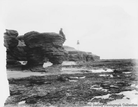 Lighthouse keeper sitting on rock formation on Point Loma beach