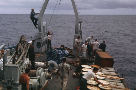 Scientific members of the Swan Song Expedition (1961) are shown here preparing to launch 50,000 gallon sample, enroute to ...
