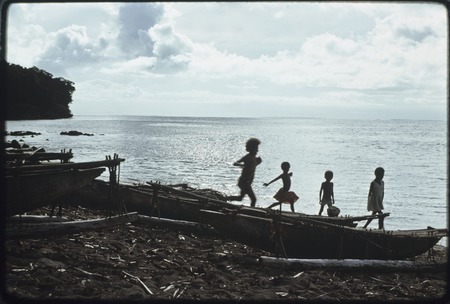 Children play by beached fishing canoes