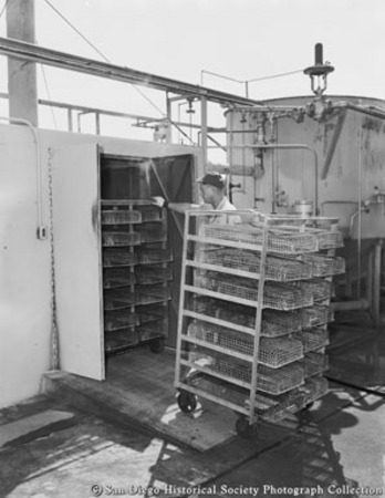 Cannery worker removing racks of tuna from precookers at Sun Harbor Packing Corporation