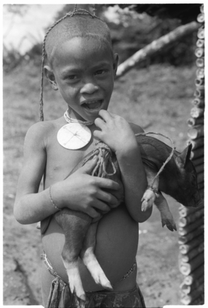 Child with pig with cord around leg.