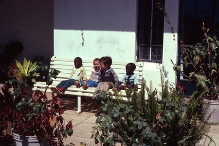Children on bench in front of a house in Kasama