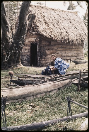 Canoes: Edwin Hutchins sits on fishing canoe, other canoes nearby, house in background