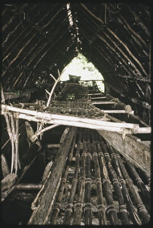 Canoes: small fishing canoe stacked on a large kula canoe in canoe-house shelter on the eastern coast of Kiriwina