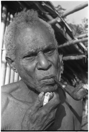 An elderly Kwaio man shaves by pulling out his whiskers with a clam shell.