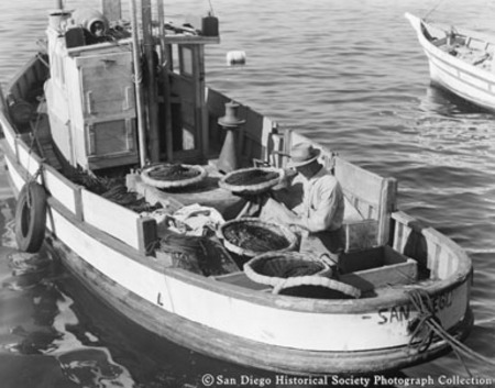 Fisherman repairing nets on docked boat