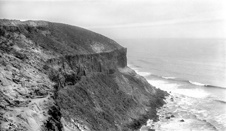 Basalt cliffs, fifty feet thick with sediments above and below, located 1/2 mile south of San Antonio del Mar, facing south