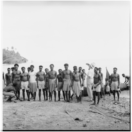 Portrait of men, boys, Father Laughman, and canoe on shore