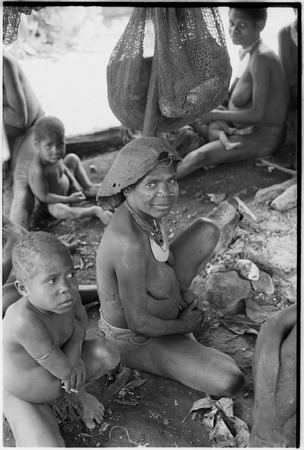 Bomagai: women and children by fire pit, child (l) holds cigarette