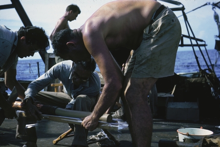Milton Nunn Bramlette (kneeling) and Roger Revelle (man without shirt) inspecting a coring device during the Capricorn Exp...