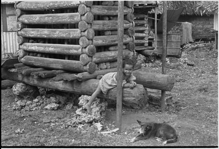 Young child and dog near a yam house