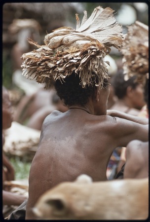 Mortuary ceremony: woman holds banana leaf bundles on her head, waiting for exchange