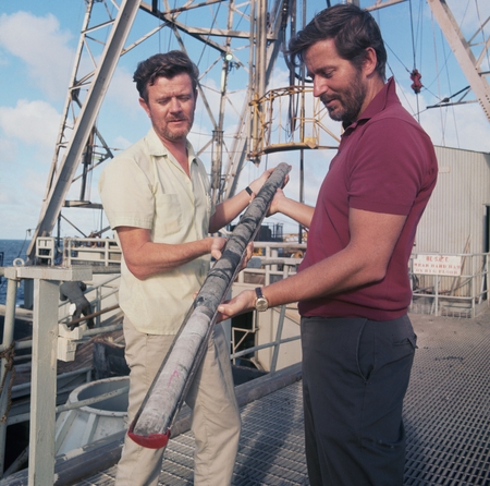 John B. Saunders (left) and scientist N. Terence Edgar (right) are shown here examining a core sample on the deck of the r...