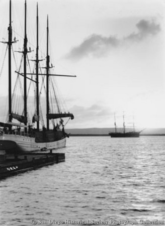 Docked lumber schooner Kona with three-masted ship in distance