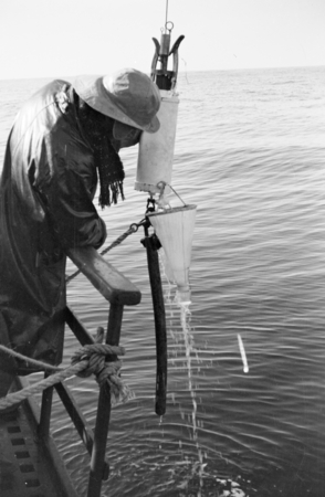 A crewmember with plankton net and sample jar, aboard R/V E.W. Scripps