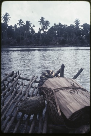 Bundle on a canoe, Tukwaukwa village in distance, Kiriwina