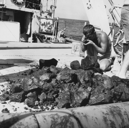 Man examining contents of dredge haul with loop