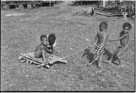 Children playing, pulling a makeshift cart in Tukwaukwa village, Kiriwina