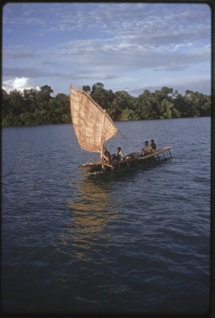 Canoe with sail up, near a small island