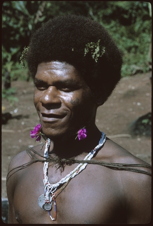 Portrait of man with purple flowers on neck.