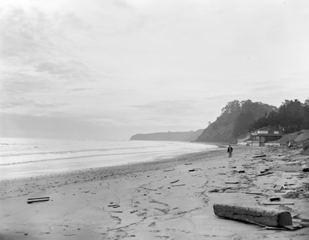Beachcomber among drift on beach looking toward Duxbury Reef on the horizon, circa 1950