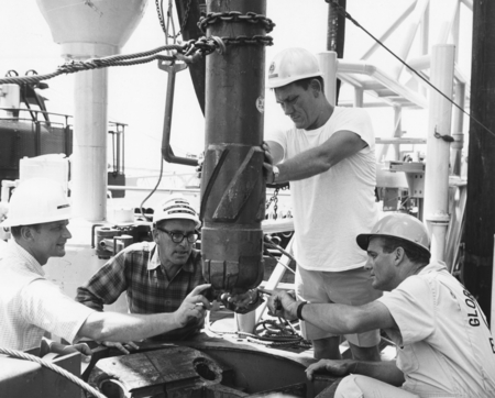 William A. Nierenberg, SIO Director, second from left, inspects a tungsten drill bit with a group of DSDP officials aboard...