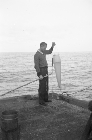 Cecil Ray Monk, a graduate student at the Scripps Institution of Oceanography, holds a plankton net aboard the R/V Scripps