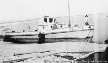 People posing with beached fishing boat Kelpie