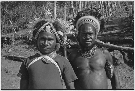 Man (l) wears luluai badge and wig, man (r) with feather and marsupial fur headdress