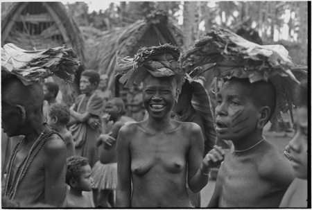 Mortuary ceremony, Omarakana: mourning women, their heads shaved, carry banana leaf bundles (wealth items) for ritual exch...