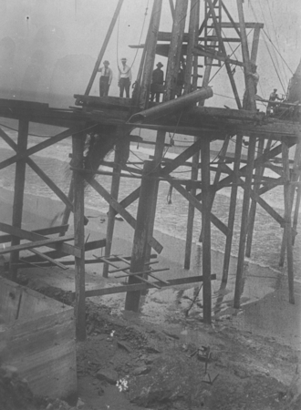 Workers emptying the sand bucket during construction of the pier at the Scripps Institution for Biological Research, which...