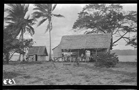 European man with Solomon Islanders in front of dwelling