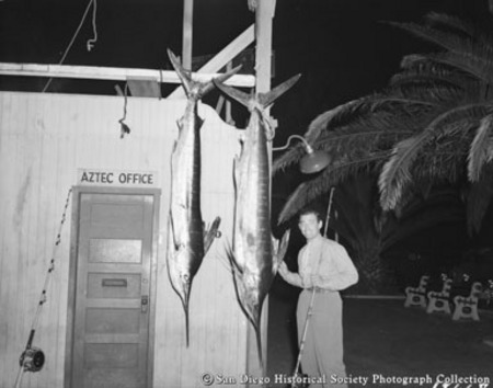 Clark Gable with fishing rod posing with swordfish caught from sportfishing boat Aztec