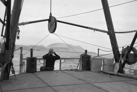 [Man viewing island from fantail of R/V Spencer F. Baird]