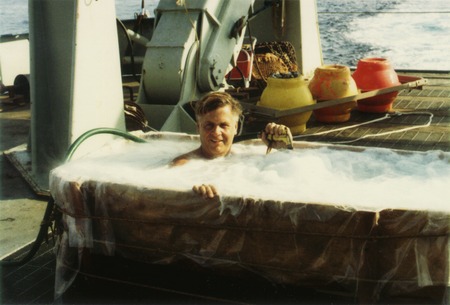 Harmon Craig bathing in a tub on deck on a research ship, n.d.