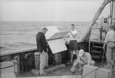 [John Knauss and crewmen with oceanographic instrument aboard R/V HORIZON]