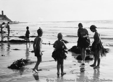Children on beach wearing kelp skirts