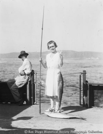 Woman posing with fishing rod and fish caught from Point Loma fishing barge