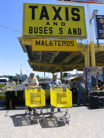 Maleteros: porters with shopping carts in front of taxi stand and bus station