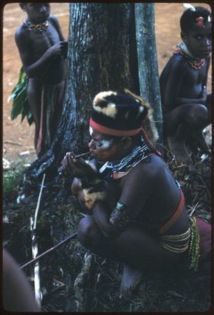 Pig festival, singsing, Kompiai: dancer in marsupial fur headdress smokes