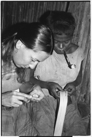 Shelley Schreiner plaits tokila armband, while Moruka works with a piece of bark.