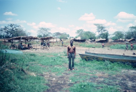 A fisherman poses near some boats at Kasongole village