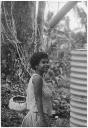 Smiling young woman, standing next to a water tank (cistern)