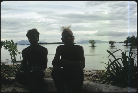 Two men seated at the shoreline