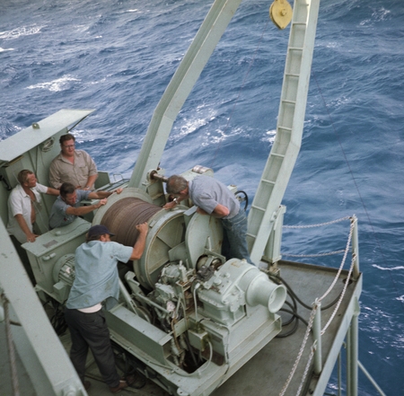 Frank Fish repairing snarled wire on fantail of ship with crew members including Bill Dahlberg in khaki